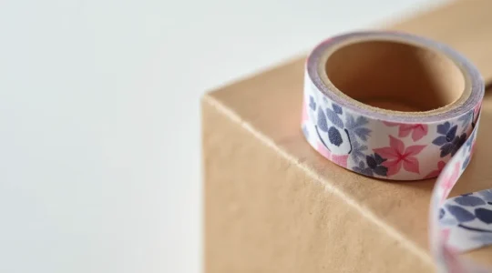 Gros plan d'un ruban adhésif personnalisé enroulé autour d'un colis, montrant l'impression du logo et les détails de conception.